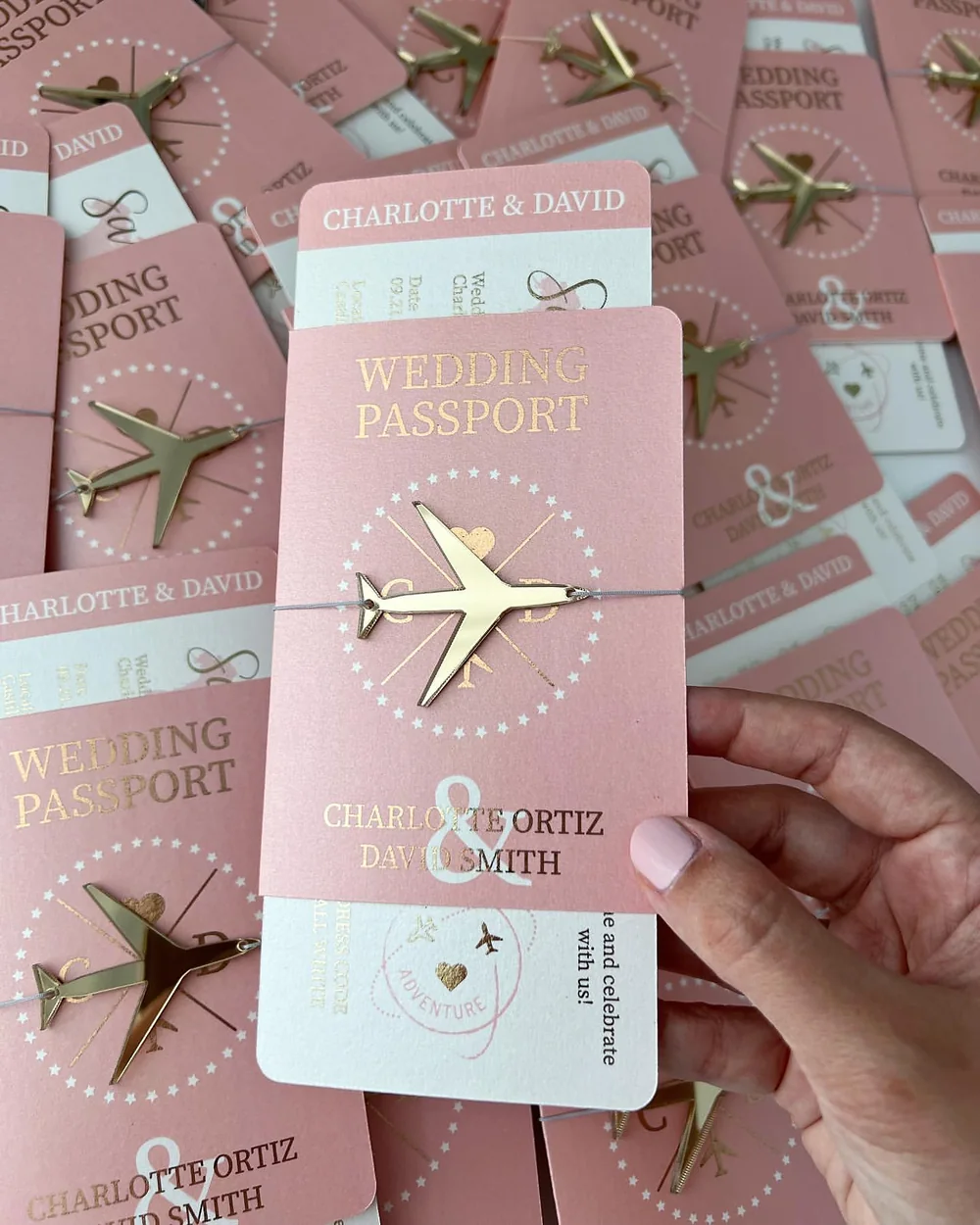 Blush passport wedding invitation with a gold airplane emblem