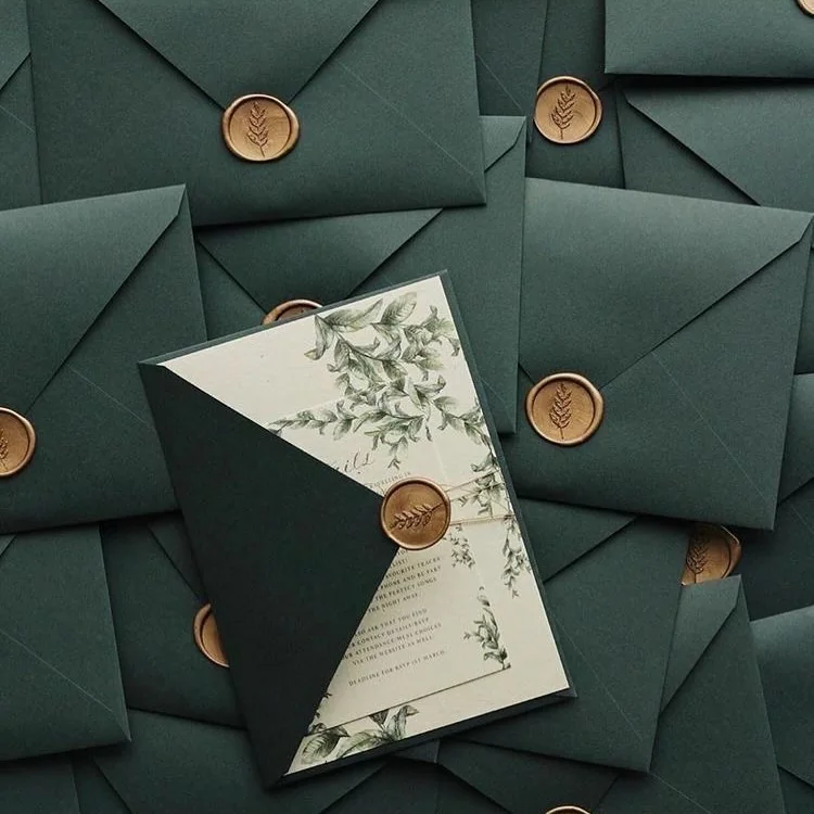 Forest-green envelopes with gold wax seals and a botanical card